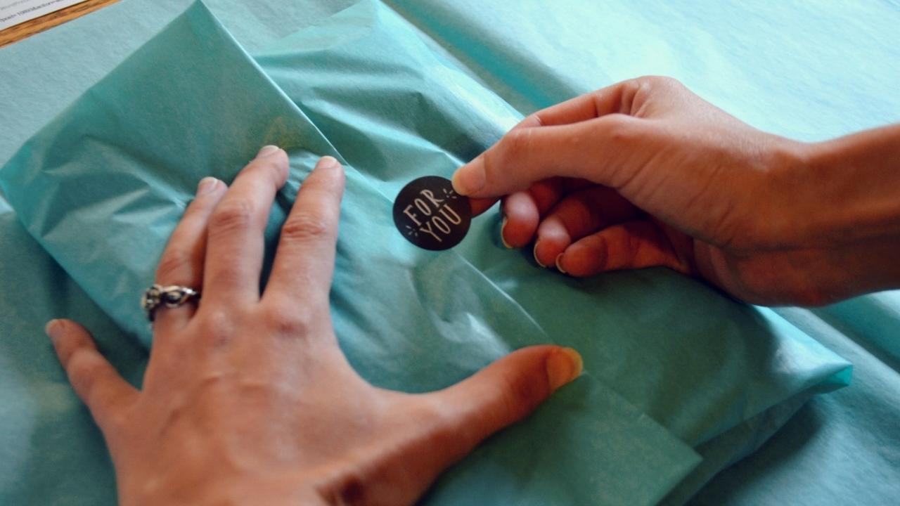 hand placing a thank you sticker on an order